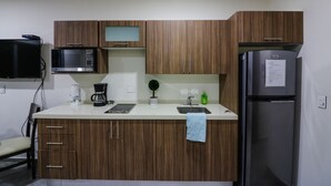 Eine kompakte Küche mit Holzausstattung, einer Mikrowelle, einer Kaffeemaschine, einem Spülbecken und einem Kühlschrank.