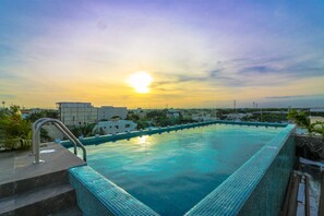 A rooftop infinity pool with a cityscape view during sunset. - The Furlough Fur303 (Playa del Carmen)