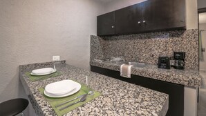 A modern kitchen with granite countertops, a built-in stove, and a coffee maker. - Apartment Fogon 003 (Playa del Carmen)