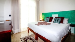 A hotel room with a bed, a nightstand, a lamp, and a wooden dresser. - Apartment Castello 1B (Playa del Carmen)