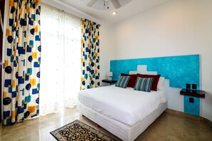 Ein Hotelzimmer mit einem großen Bett, einer blauen Akzentwand und einem gemusterten Vorhang.