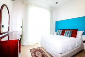 Ein Hotelzimmer mit Bett, Spiegel, Fenster mit Vorhängen und einer blauen Akzentwand.