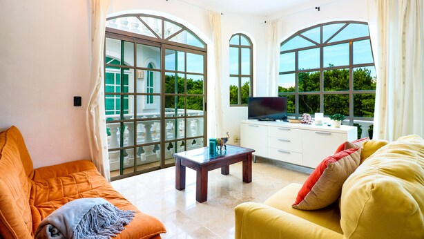A spacious living room with large windows, a flat-screen TV, and comfortable seating. - Apartment Castello 2C (Playa del Carmen)