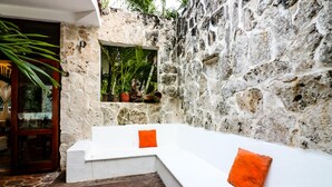 A stone-walled outdoor seating area with white benches and orange cushions. - Villa 4 Soles (Playa del Carmen)
