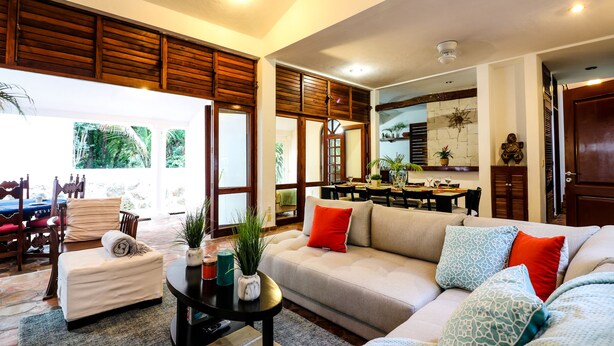 A spacious living room with a sofa, coffee table, and a dining area with a table and chairs. - Villa 4 Soles (Playa del Carmen)