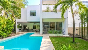 Et moderne hus med swimmingpool, en terrasse med havemøbler og en velplejet have.