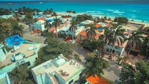Vue aérienne d’un quartier résidentiel situé sur la côte, avec des maisons, une piscine et une plage.