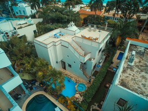 Un immeuble à plusieurs étages doté d’une piscine sur le toit, entouré de palmiers et d’autres plantes.