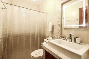 A bathroom with a shower curtain, a toilet, a sink with a mirror, and a towel rack.