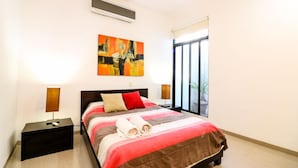 Una camera d'albergo con un letto, due comodini, una finestra vista e un quadro appeso al muro.