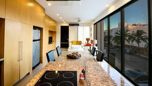 Una cocina moderna con una isla central, electrodomésticos integrados y un amplio ventanal con vistas a la ciudad.