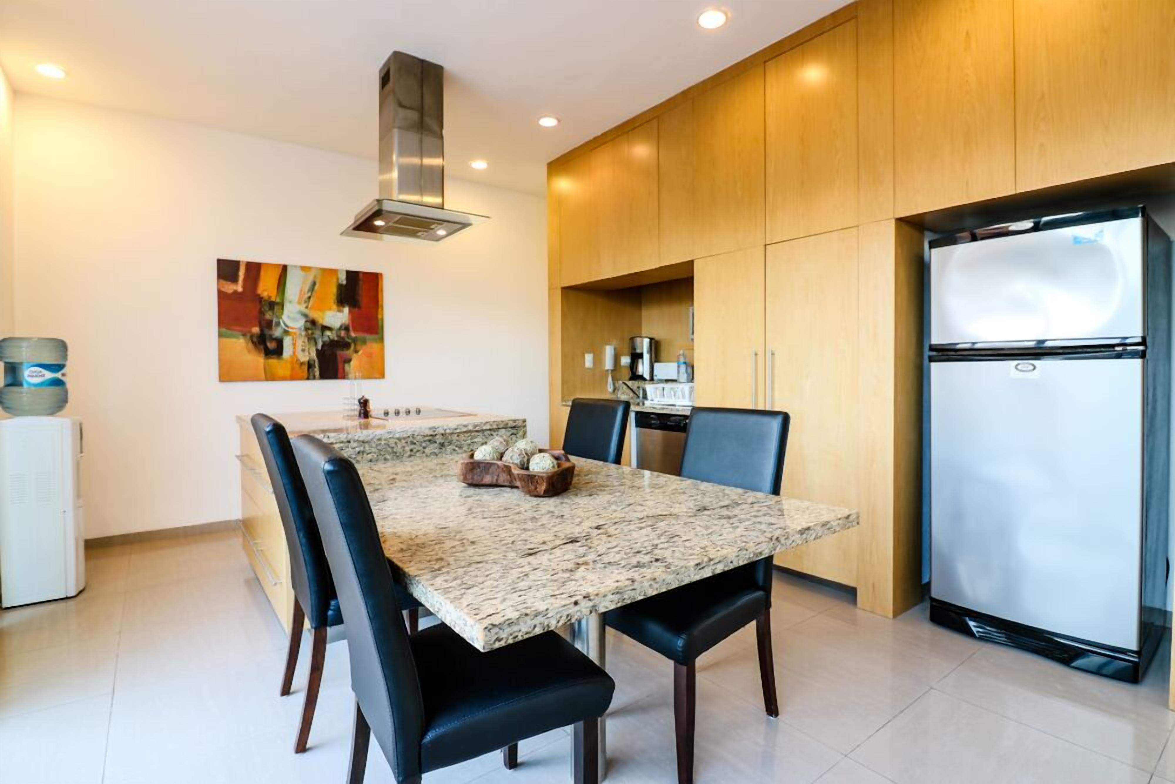 Una cucina moderna con piani di lavoro in granito, piano cottura integrato e frigorifero in acciaio inossidabile.