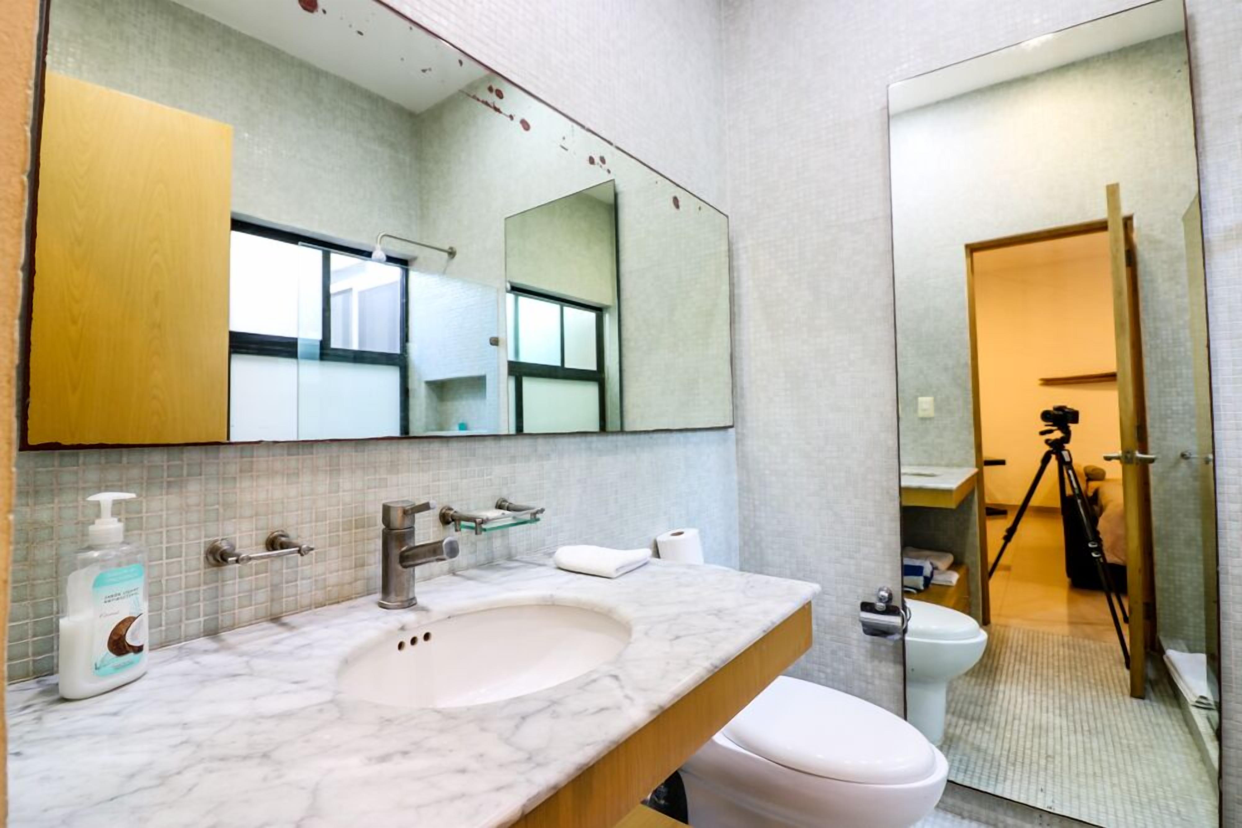 A bathroom with a marble sink, a large mirror, and a toilet.