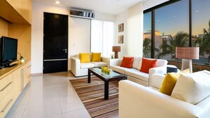 Una sala de estar moderna con un sofá, una mesa de centro y un televisor sobre un mueble de madera.