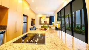 Una cocina moderna con una isla central, electrodomésticos integrados y grandes ventanales con vistas al exterior.