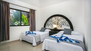 A hotel room with two beds, a large window with curtains, a wall-mounted tree decoration, and a bedside table with a lamp. - Casa 20 (Playa del Carmen)