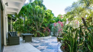 An outdoor patio area with a checkered floor, wicker furniture, and lush tropical plants. - Casa 20 (Playa del Carmen)