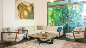 A living room with a sofa, two armchairs, a coffee table, and a painting on the wall. - Casa 20 (Playa del Carmen)