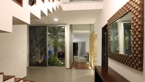 Um interior moderno com escada, porta de vidro que dá para uma varanda e um espelho grande.