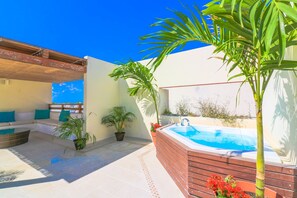 Een terras op het dak met een jacuzzi, een zithoek en potplanten.