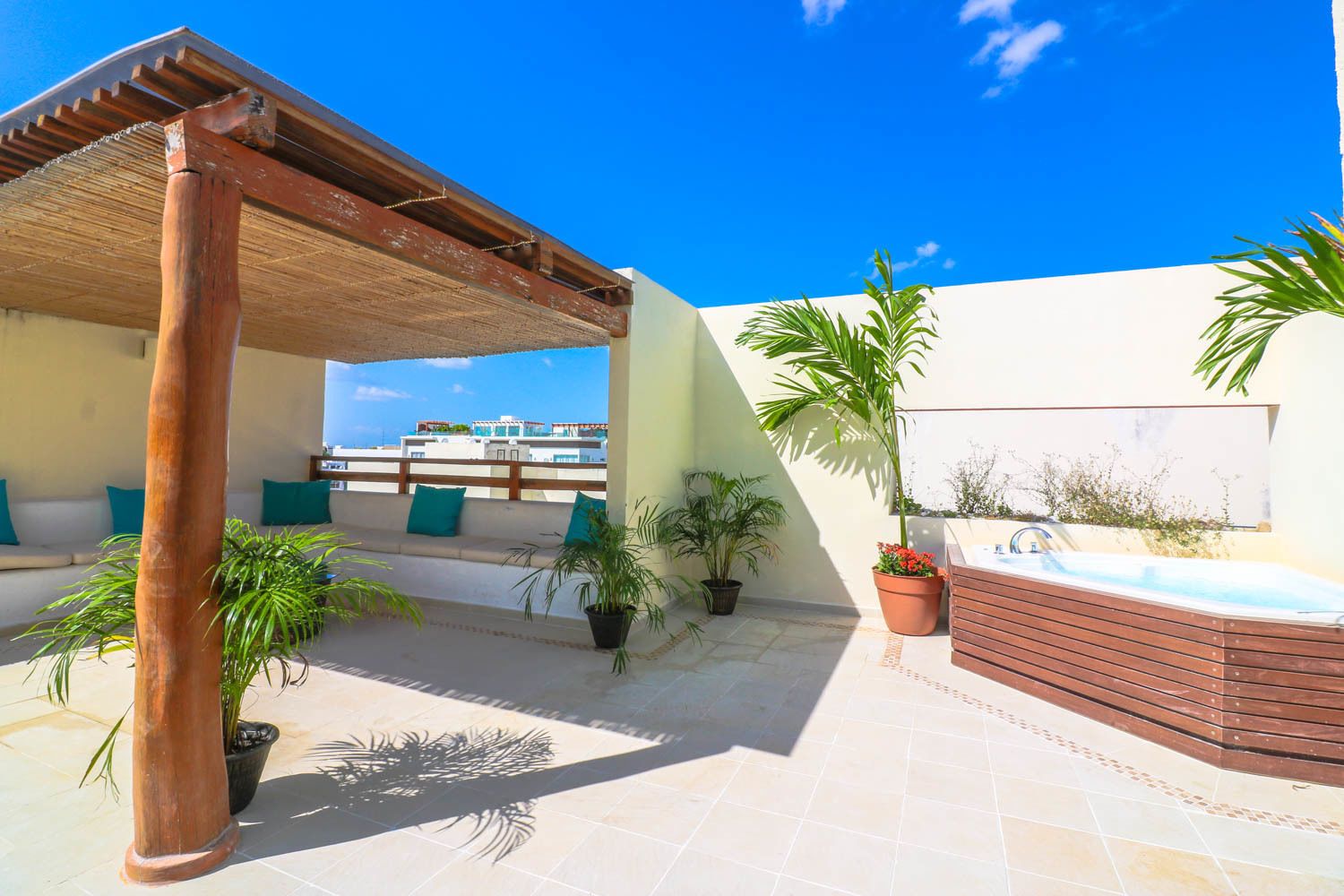 A rooftop terrace with a wooden pergola, outdoor seating, potted plants, and a hot tub.