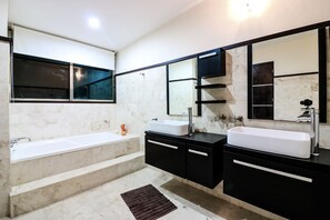 Une salle de bain moderne avec une baignoire, deux lavabos, un grand miroir et une fenêtre.