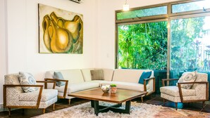 A living room with a sofa, two armchairs, a coffee table, and a painting on the wall. - Villa Compound (Playa del Carmen)
