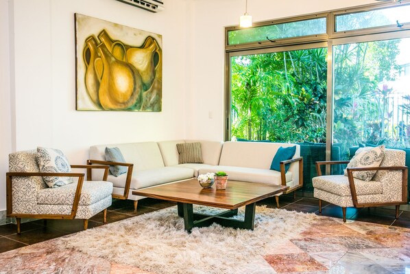Una sala de estar con un sofá, dos sillones, una mesa de centro y un cuadro en la pared.