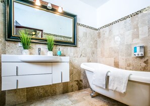 Un baño con tocador blanco, un espejo grande y una bañera.