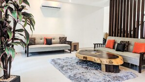 Un salon moderne avec deux canapés, une table basse et une grande plante en pot.