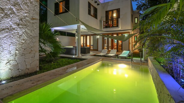 Une maison moderne dotée d’une piscine, d’un espace salon extérieur et d’une terrasse bien éclairée.