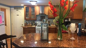 A kitchen with wooden cabinets, a copper-toned island, and a vase with red flowers.