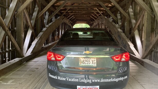 A car parked in a covered wooden structure with a metal roof.