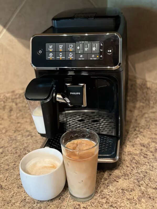 Une machine à café dotée d’un panneau de commande et de deux tasses de café.