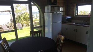 A kitchen with a view of a garden and a body of water. - MUDBRICK BARN MUDENZA VU (Opononi)