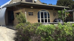 A house with a curved roof, a large window, and a satellite dish. - MUDBRICK BARN MUDENZA VU (Opononi)