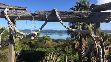 A rustic wooden structure with a rope swing, surrounded by lush greenery and a view of a lake.