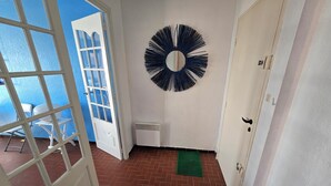 A hallway with a white door, a black circular wall decoration, and a green mat on the floor.