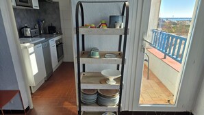 A kitchen with a metal rack holding plates and bowls, a toaster, and a kettle.