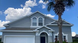 A two-story house with a garage, a front door, and a palm tree. - Mickeys Paradise Glenbrook Resort -5* Bed, 3 &1/2 Bath Villa with Pool and Spa. (Clermont)