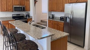 A kitchen with granite countertops, wooden cabinets, a stainless steel refrigerator, a microwave, and a stove. - Mickeys Paradise Glenbrook Resort -5* Bed, 3 &1/2 Bath Villa with Pool and Spa. (Clermont)