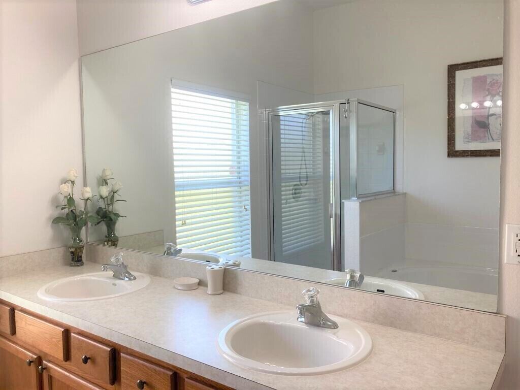 Un baño con dos lavamanos, un espejo grande y cabina de ducha.