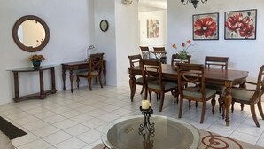 A dining area with a round glass table, wooden chairs, and a chandelier. - Mickeys Paradise Glenbrook Resort -5* Bed, 3 &1/2 Bath Villa with Pool and Spa. (Clermont)