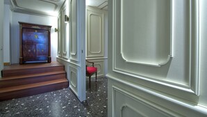 Ein Flur mit einer Holztreppe, einem roten Stuhl und einer Tür mit dekorativer Verzierung.