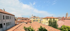 A view from a private terrace with terracotta tiled roofs, potted plants, and a clear sky.