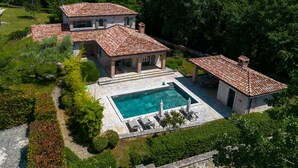 A large house with a swimming pool, surrounded by lush greenery. - Luxury villa with heated pool (Višnjan)