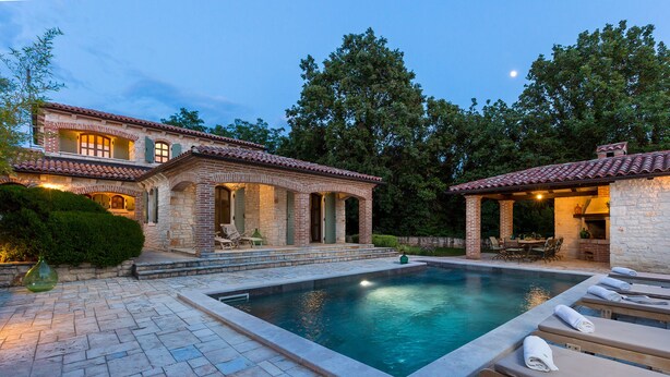 A poolside area with a stone building, outdoor seating, and a clear sky. - Luxury villa with heated pool (Višnjan)