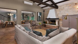 A spacious living room with a high ceiling, exposed wooden beams, a fireplace, and a dining area with a view of the kitchen. - Luxury villa with heated pool (Višnjan)