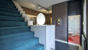 A staircase with blue steps leading to a landing with a white circular light fixture. - ARNOLDI~Rooftop (Venezia)