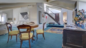 A spacious living room with a dining area, a staircase, and a large floral arrangement. - ARNOLDI~Rooftop (Venezia)